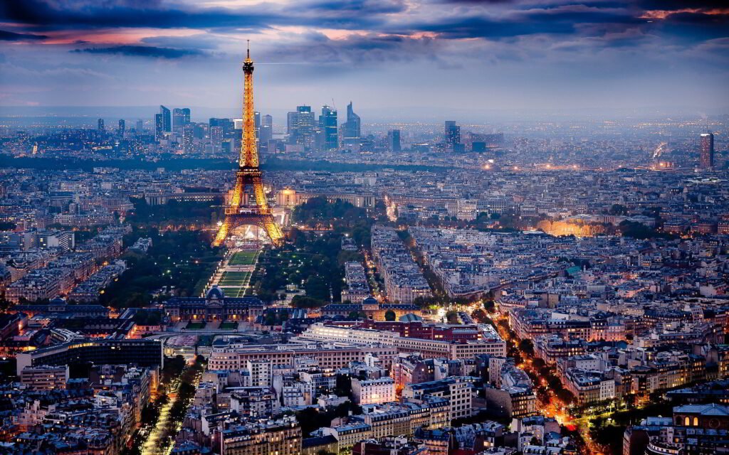 A stunning view of the Eiffel Tower illuminated at night, with the Paris skyline and city lights in the background.
